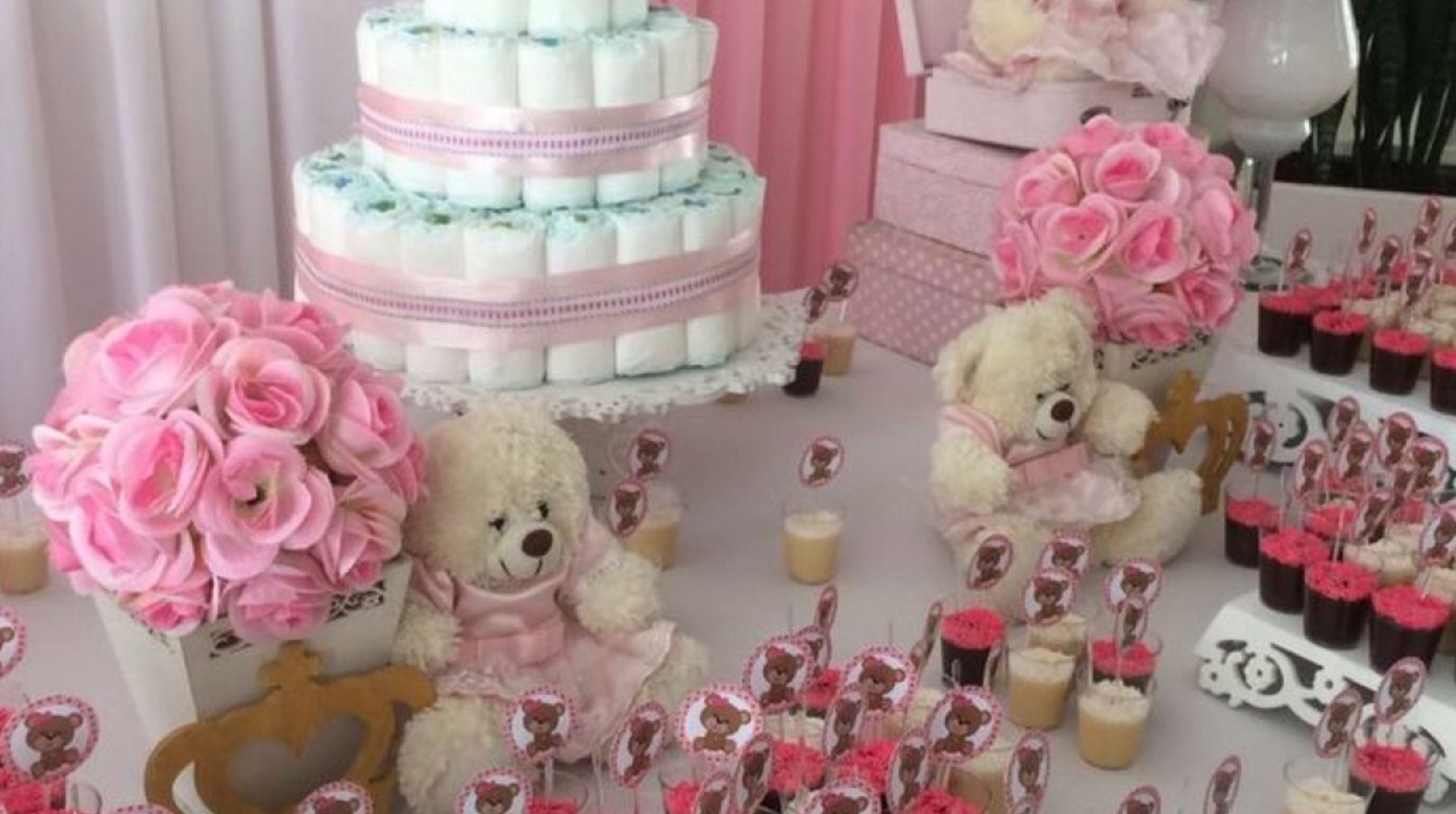 Baby shower table with a diaper cake, pink roses and teddy bears