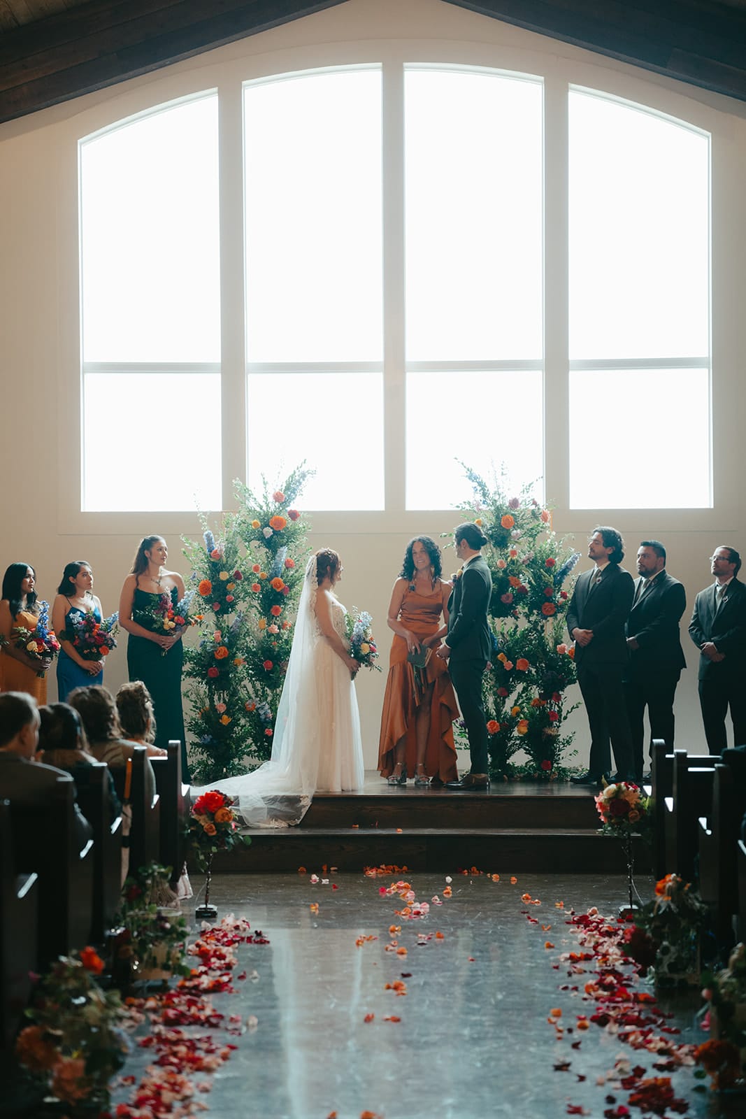 Wedding ceremony seen from the aisle, with petals lining the floor
