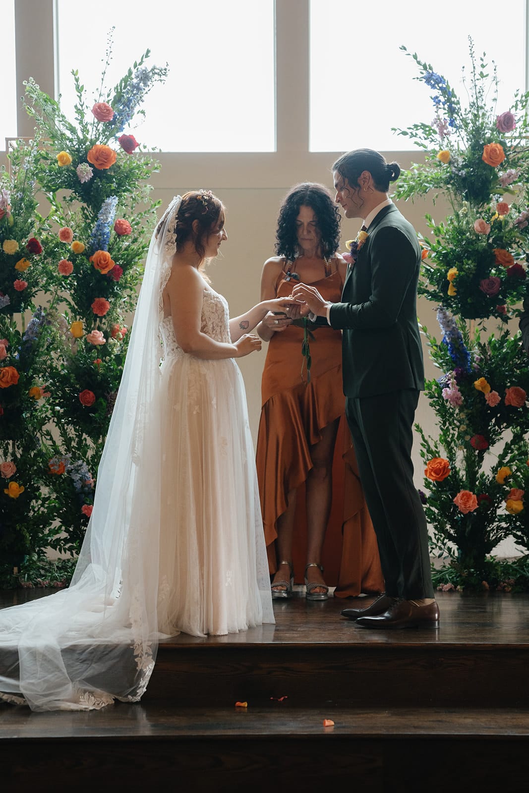 Couple exchanging vows at an altar framed by tall floral arrangements