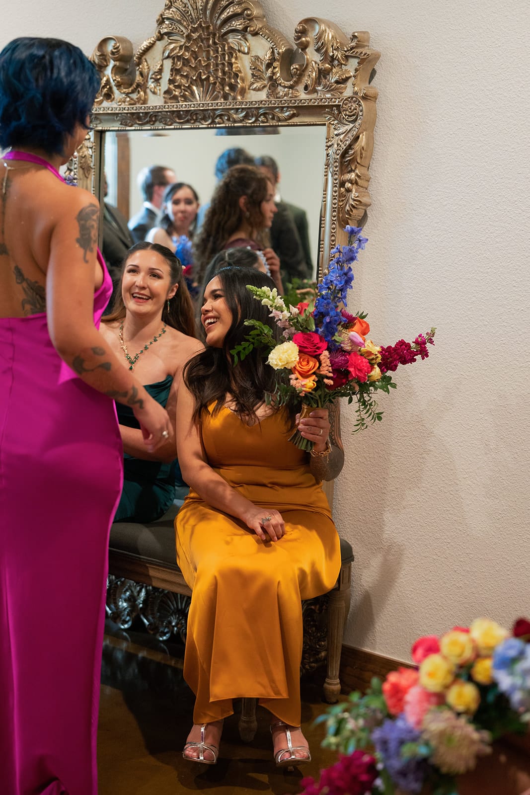 Bridesmaids in mustard and magenta dresses holding bouquets