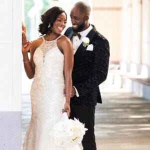 Funto and Raymond smiling at each other, the bride holding white flowers