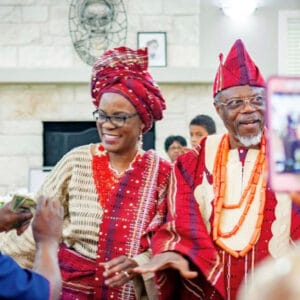 Couple in red Nigerian attire and coral beads at Toyin's mother's birthday celebration